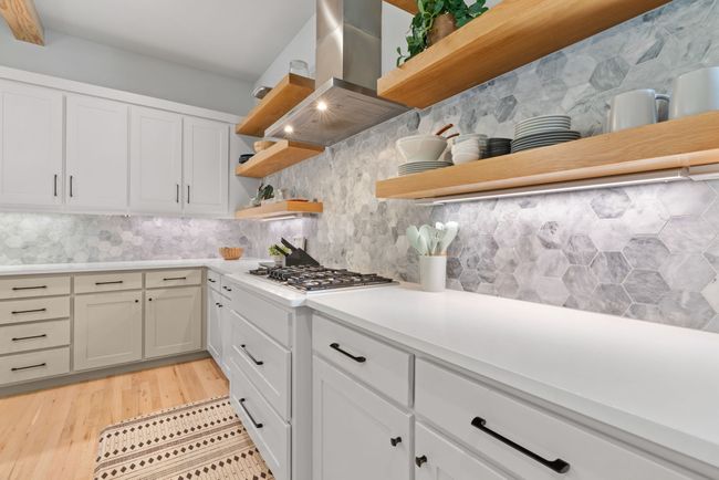 Kitchen with open shelves, island range hood, stainless steel gas cooktop, and decorative backsplash | Image 17