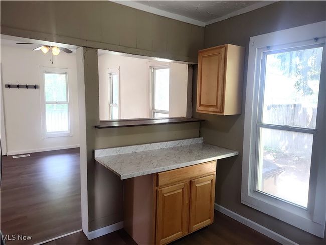 Kitchen with dark wood finished floors, ceiling fan, baseboards, crown molding, and light stone countertops | Image 25