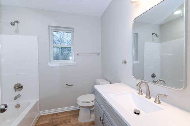 Bathroom with baseboards, toilet, vanity, wood finished floors, and washtub / shower combination | Image 17