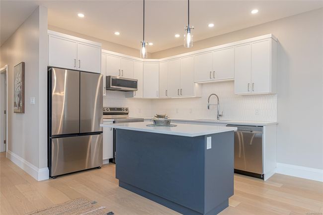 Beautiful Kitchen with quartz coutners, tiled backsplash, stainless steel appliances and eat-at island | Image 13