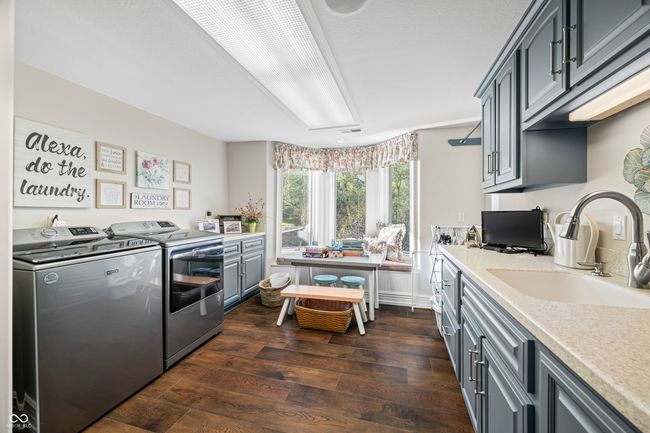 laundry room with dark wood finished floors, washing machine and clothes dryer, light countertops, a sink, and gray cabinetry | Image 54