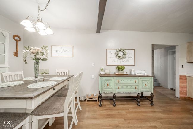 dining area featuring light wood finished floors, beamed ceiling, and a notable chandelier | Image 24