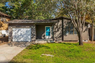 View of front facade with cooling unit, a front yard, and a garage | Image 1