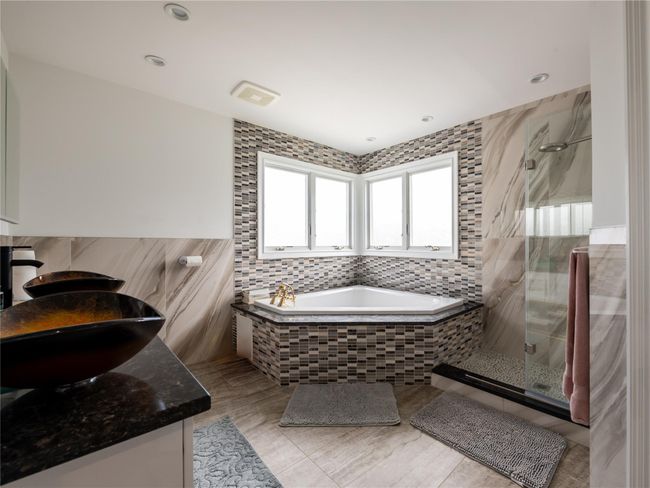 Full bath with a bath, a sink, double vanity, a stall shower, and tile walls | Image 18