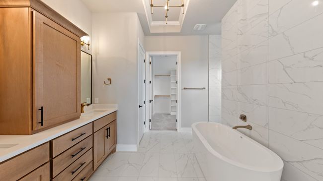 Bathroom featuring a spacious closet, a freestanding tub, tile walls, and light marble finish flooring | Image 25