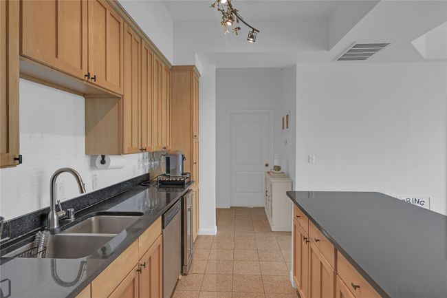 Kitchen with dark stone countertops, stainless steel dishwasher, and light brown cabinetry | Image 5