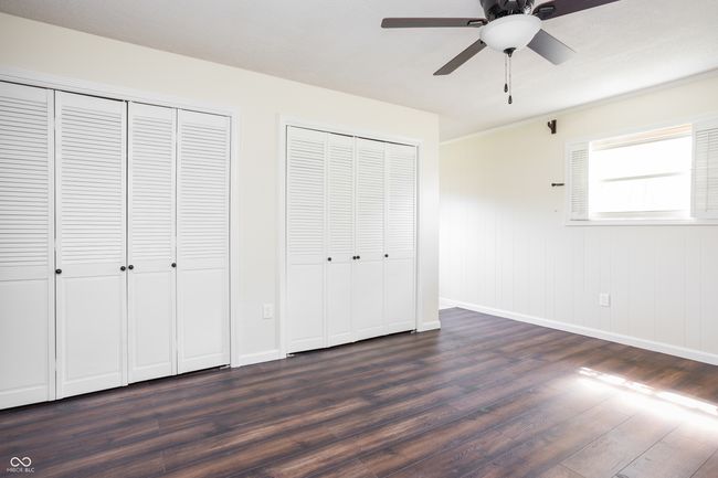 unfurnished bedroom with dark wood-style flooring, two closets, and a ceiling fan | Image 26