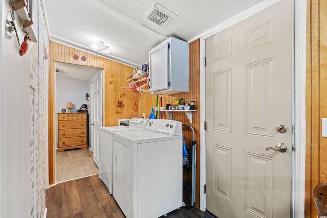 Laundry area featuring separate washer and dryer, cabinet space, wood walls, crown molding, and dark wood-style flooring | Image 19