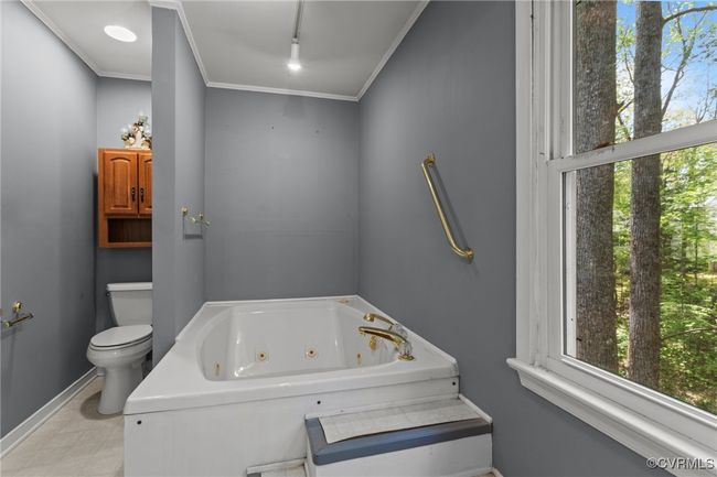 Bathroom featuring baseboards, toilet, a tub with jets, and plenty of natural light | Image 22