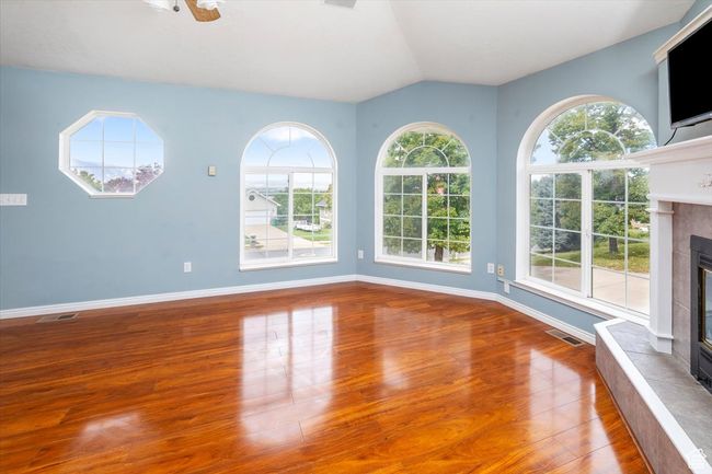 Unfurnished living room featuring a fireplace, vaulted ceiling, hardwood / wood-style floors, and plenty of natural light | Image 6