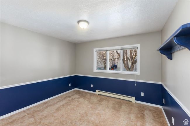 Carpeted spare room featuring baseboards, a baseboard heating unit, and a textured ceiling | Image 14