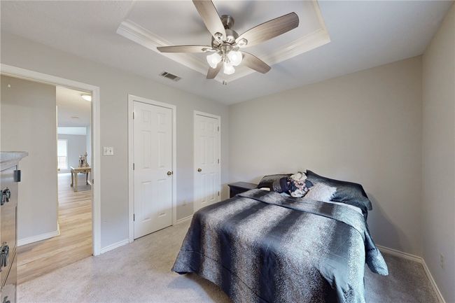 Bedroom featuring light colored carpet, baseboards, a tray ceiling, and ceiling fan | Image 15