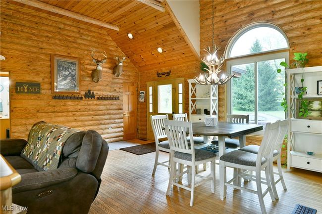Dining space featuring hardwood / wood-style floors, wood ceiling, healthy amount of natural light, log walls, and a chandelier | Image 10