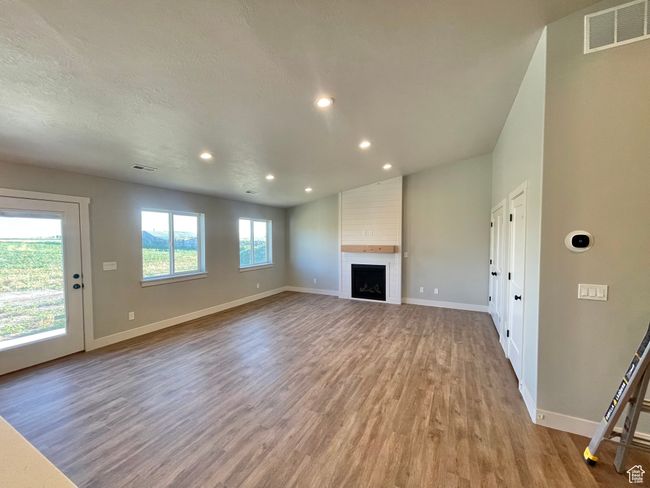 Unfurnished living room featuring baseboards, visible vents, light wood finished floors, and recessed lighting | Image 9