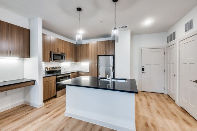 Kitchen with dark countertops, visible vents, stainless steel appliances, and brown cabinetry | Image 10