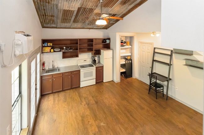 Apartment kitchen featuring white appliances, open, metal and wood ceiling, wood finished floors | Image 35