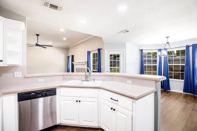 Kitchen with dishwasher, a ceiling fan, dark wood finished floors, light countertops, and crown molding | Image 25