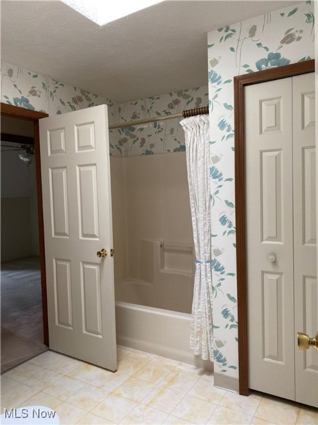 Bathroom featuring wallpapered walls, shower / bathtub combination with curtain, and a textured ceiling | Image 11