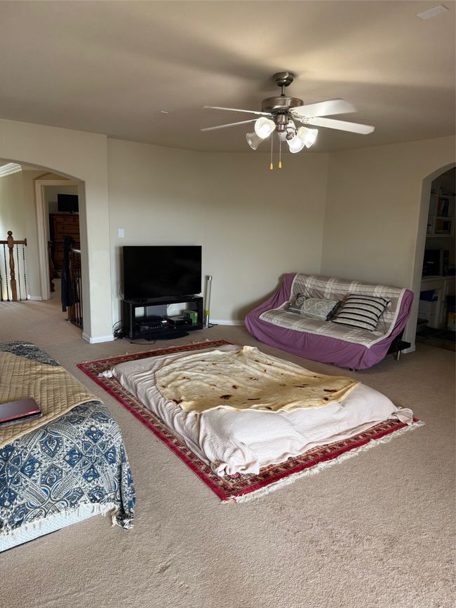 Carpeted living area with arched walkways, a ceiling fan, and baseboards | Image 33