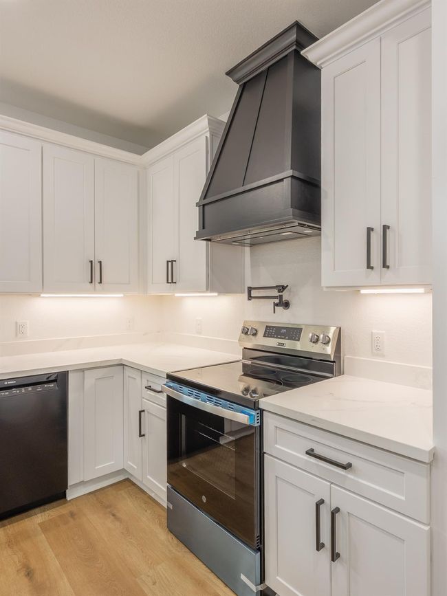 Elevate your culinary experience with this sleek stainless steel electric range, flanked by soft-close white cabinetry and topped with a stunning matte black custom range hood—creating a bold contrast that feels both modern and timeless. | Image 17