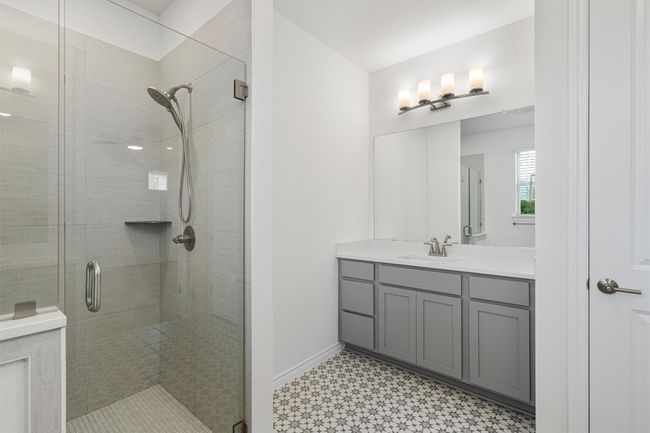 Primary bath showing a close view of the shower and one of the vanities with quartz countertops | Image 14