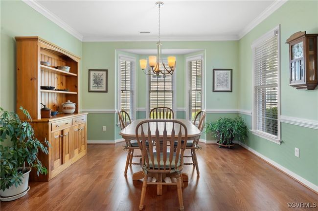 Dining area featuring a chandelier, wood finished floors, and crown molding | Image 9