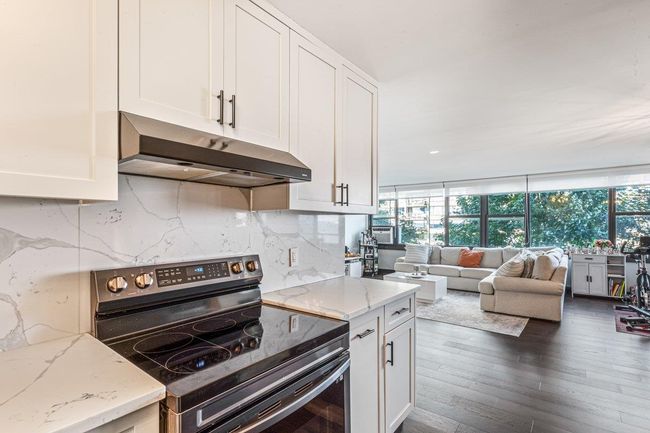 Kitchen featuring stainless steel electric range, under cabinet range hood, healthy amount of natural light, and white cabinets | Image 17
