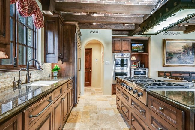 Kitchen featuring brick ceiling, stainless steel appliances, a sink, arched walkways, and stone tile flooring | Image 13