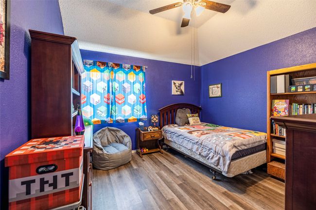 Bedroom featuring a textured wall, lofted ceiling, wood finished floors, a ceiling fan, and a textured ceiling | Image 28