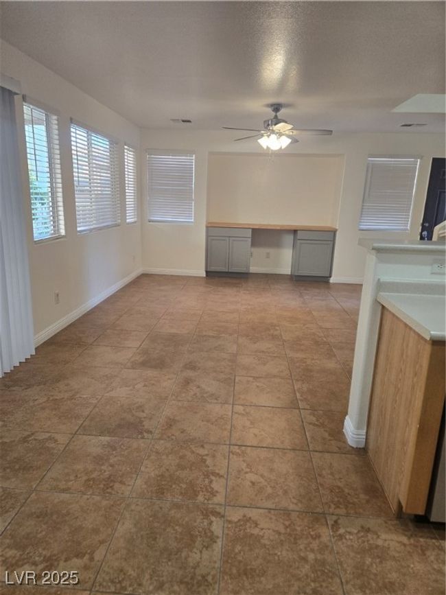 Unfurnished dining area featuring tile patterned flooring, built in study area, visible vents, and a ceiling fan | Image 6