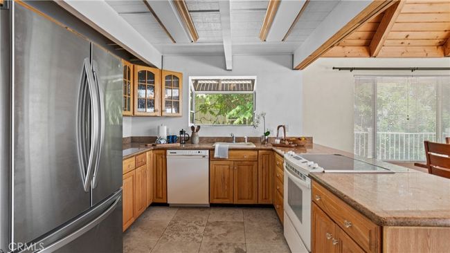 Kitchen features travertine floor tiles, granite counter-tops, a garden window. | Image 11