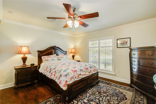The second secondary bedroom, slightly larger than the first, mirrors the same neutral paletteand crown molding, complemented by warm woodfloors that add a cozy touch. | Image 24