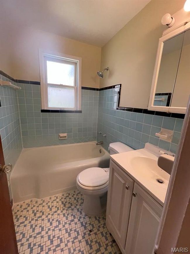 Bathroom with tile patterned floors, toilet, vanity, tile walls, and shower combination | Image 17