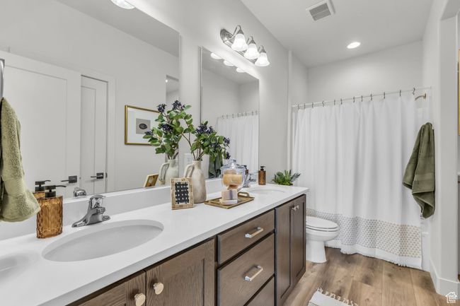 Full bathroom featuring shower / bath combination with curtain, vanity, hardwood / wood-style flooring, and toilet | Image 21