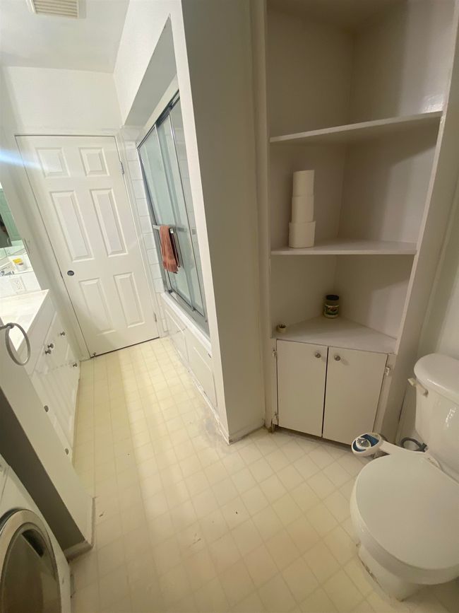 Full bath with combined bath / shower with glass door, toilet, vanity, and visible vents | Image 12