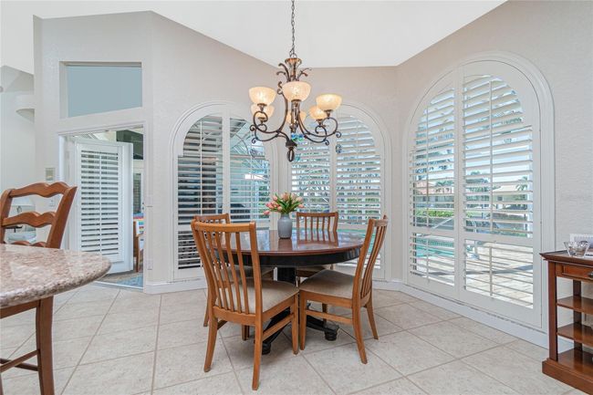 Kitchen nook with door to lanai and full length windows overlooking pool with plantation shutters | Image 14