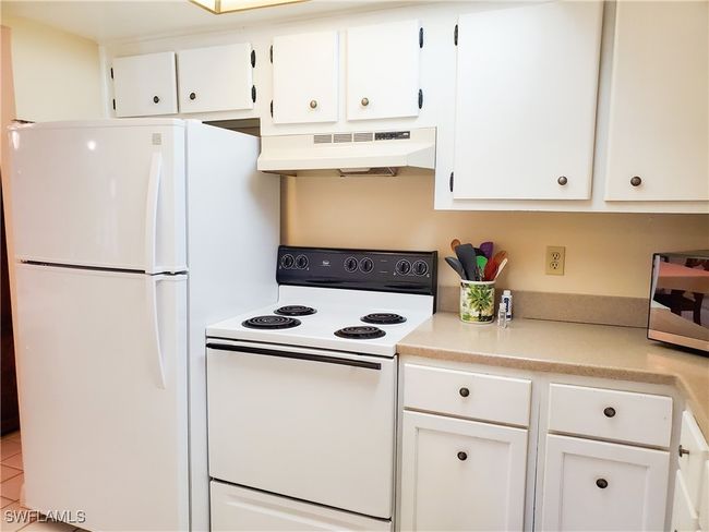 Kitchen with white cabinetry, under cabinet range hood, and white appliances | Image 12