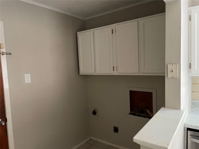 Washroom featuring hookup for an electric dryer, washer hookup, cabinet space, tile patterned floors, and ornamental molding | Image 5