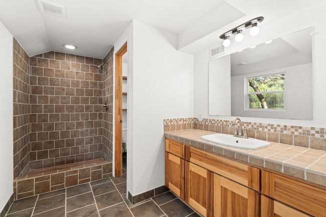 Downstairs bathroom with tiled shower and vanity, with decorative backsplash | Image 25