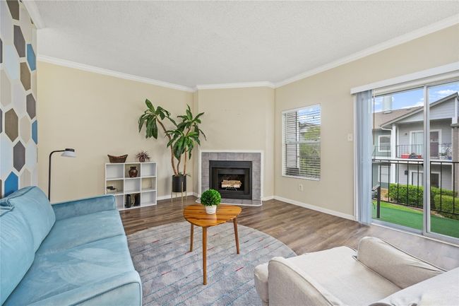 Living area with wood finished floors, ornamental molding, a fireplace, baseboards, and a textured ceiling | Image 7