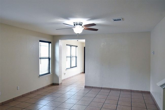Empty room featuring light tile patterned floors, baseboards, visible vents, and a ceiling fan | Image 4