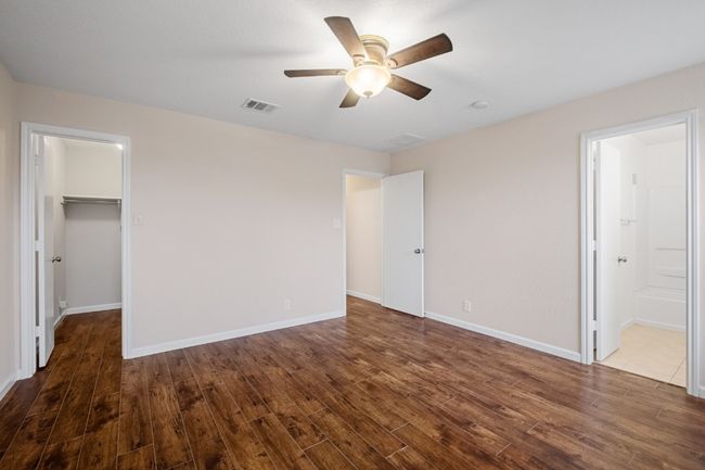 Unfurnished bedroom featuring dark wood finished floors, a spacious closet, ceiling fan, a closet, and connected bathroom | Image 23