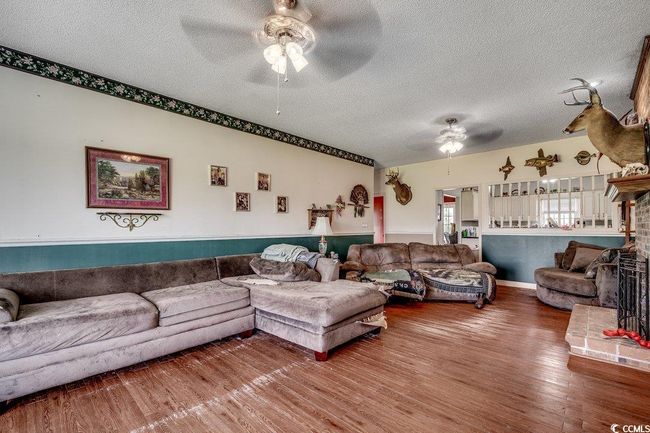 Living area featuring a ceiling fan, a textured ceiling, and wood finished floors | Image 10