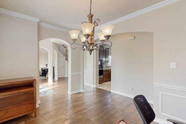 Unfurnished dining area with arched walkways, a notable chandelier, crown molding, and light wood-type flooring | Image 14