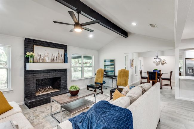 Living room with a brick fireplace, light wood-style flooring, ceiling fan, and a chandelier | Image 9