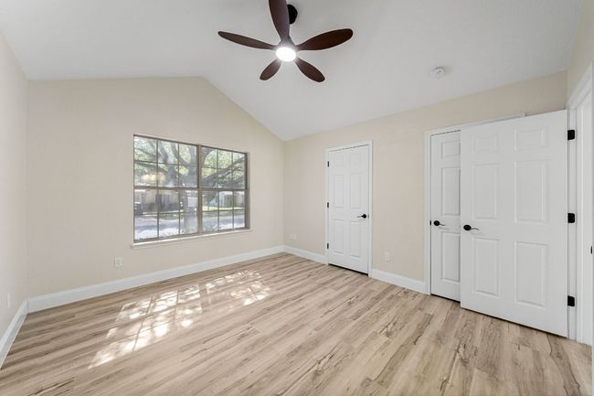 Unfurnished bedroom with wood finished floors, vaulted ceiling, and ceiling fan | Image 30