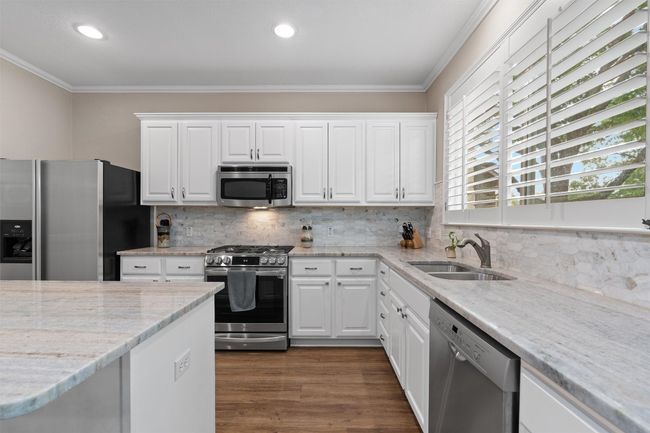 Kitchen with appliances with stainless steel finishes, a sink, crown molding, white cabinets, and recessed lighting | Image 10