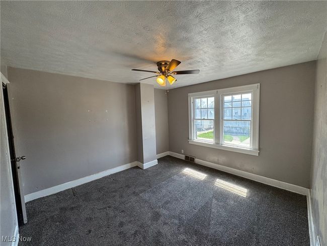 Bedroom with dark carpet, a textured ceiling, baseboards, and ceiling fan | Image 12