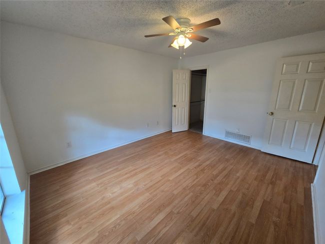 Unfurnished bedroom with light wood finished floors, a textured ceiling, ceiling fan, a closet, and a walk in closet | Image 15