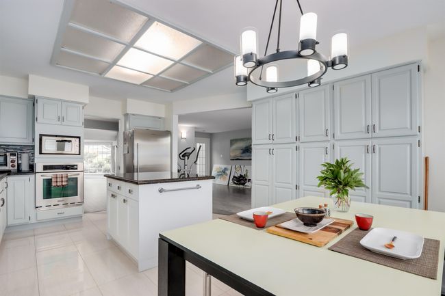 Kitchen with appliances with stainless steel finishes, a center island, dark countertops, hanging light fixtures, and a chandelier | Image 10